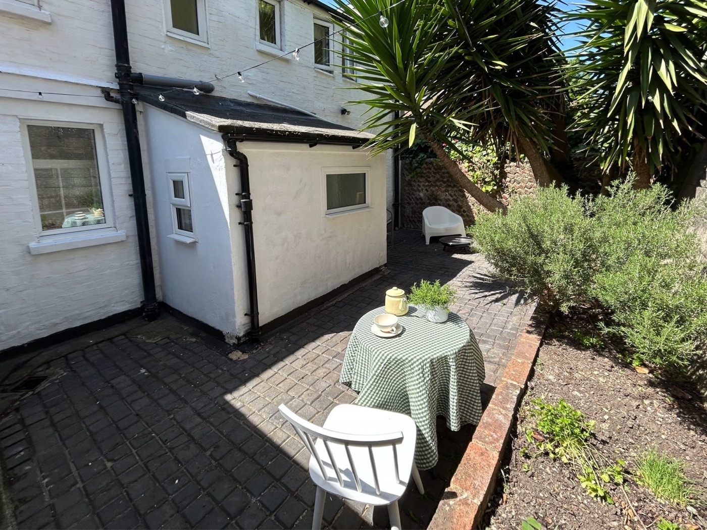 Private rear courtyard with table and chairs beneath a mature tree